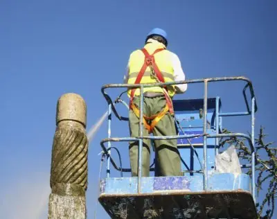 Worker cleaning concrete with a jet washer at height Worker high level industrial cleaning